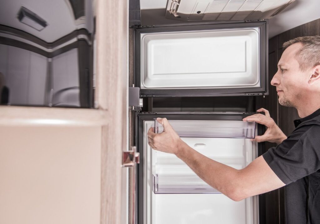 RV kitchen with technician inspecting a microwave and fridge for repair