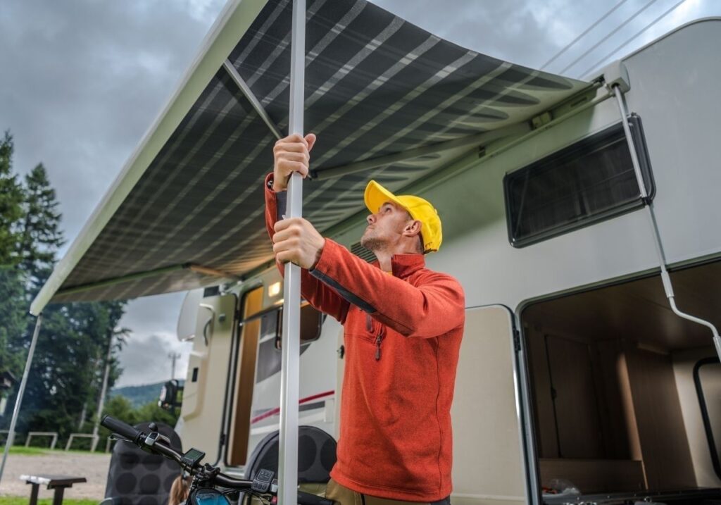 Close-up of an RV awning mid-repair with exposed fabric and arms
