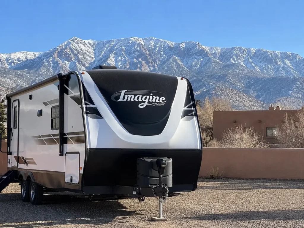 Travel trailer parked in Albuquerque driveway on crisp winter morning with snow-capped Sandia Mountains mobile RV winterization service Albuquerque NM